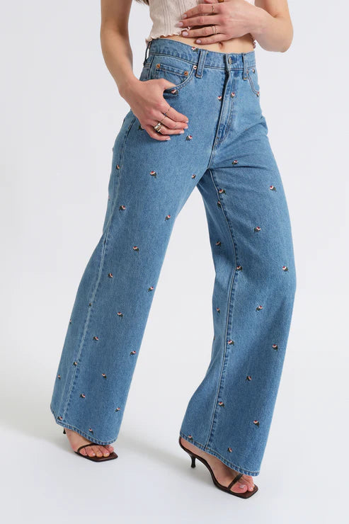 Blue jeans with decorative studs worn by a person on a white background