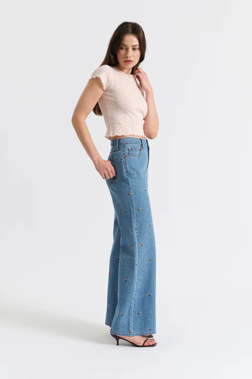 Woman wearing a light pink top and blue jeans on a white background
