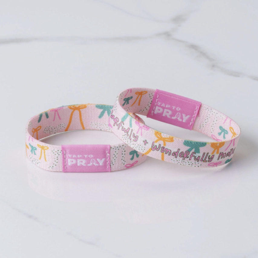 Pink wristband with colorful designs and text on a light gray background