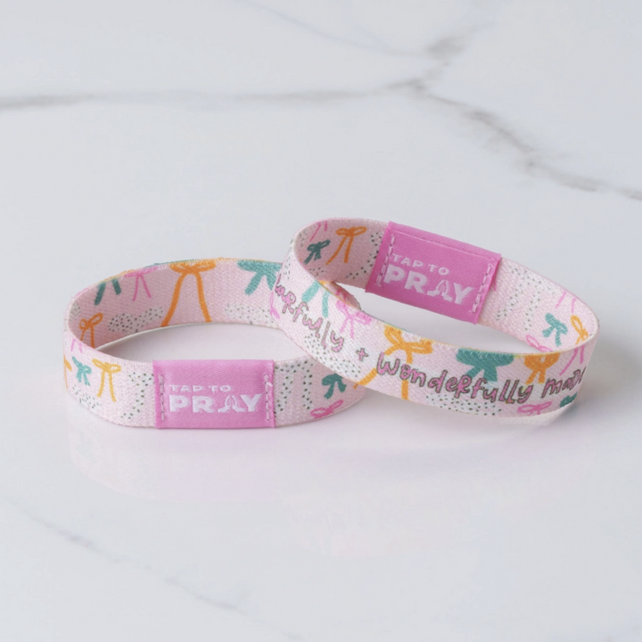 Pink wristband with colorful designs and text on a light gray background