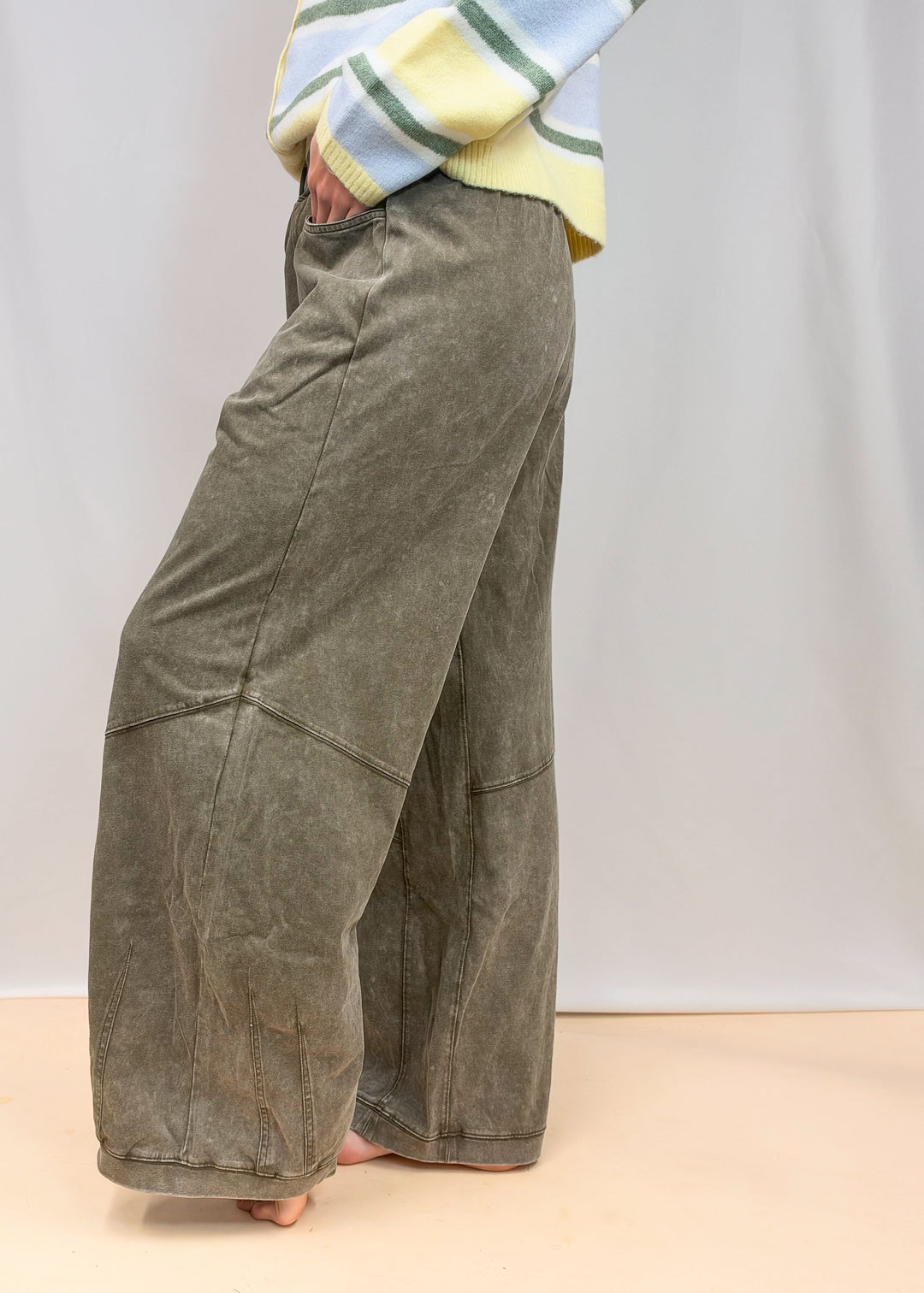Woman shown from waist down wearing green sweatpants on plain background