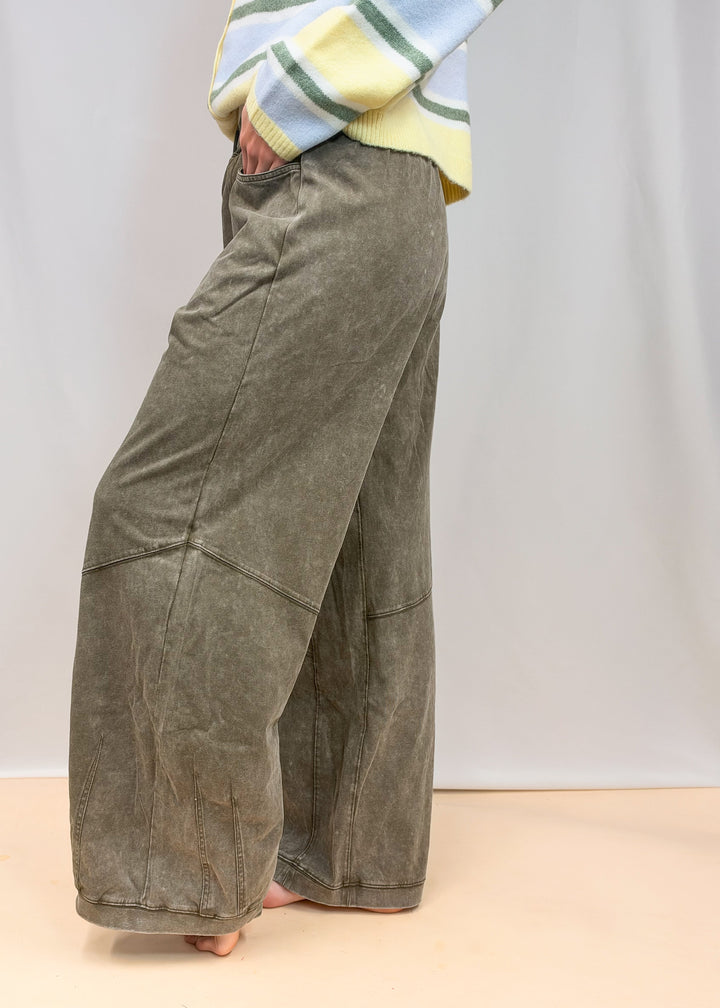 Woman shown from waist down wearing green sweatpants on plain background