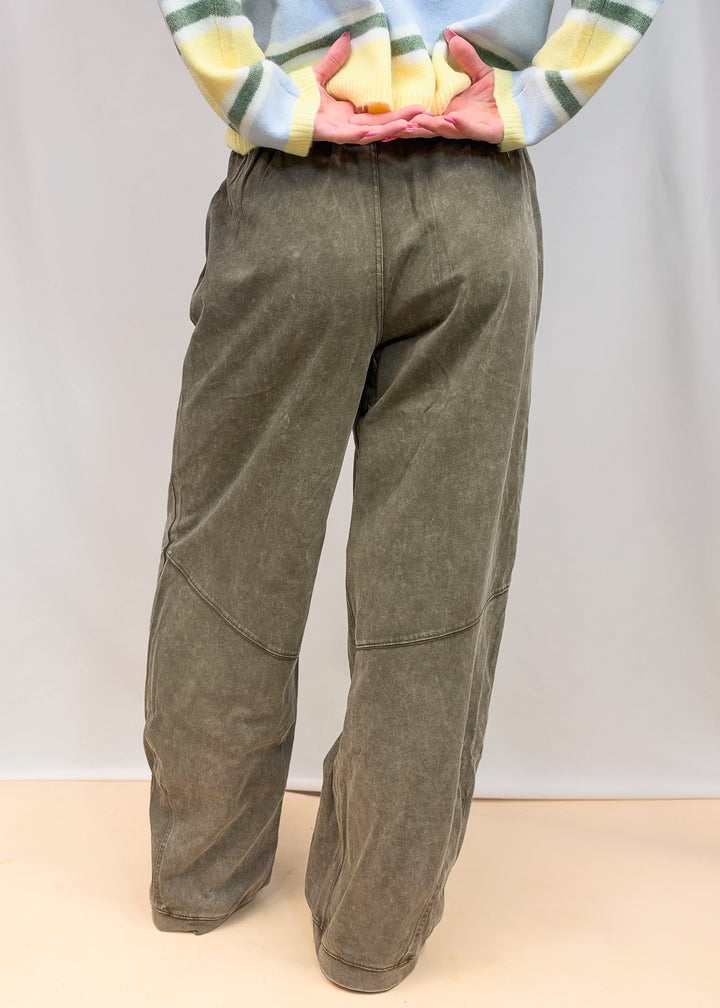 Woman shown from waist down wearing green sweatpants on plain background
