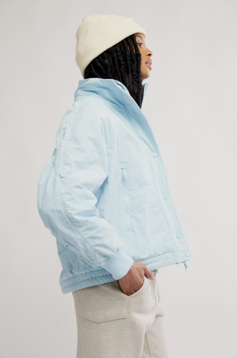 Person wearing a light blue jacket and beige beanie on a plain background