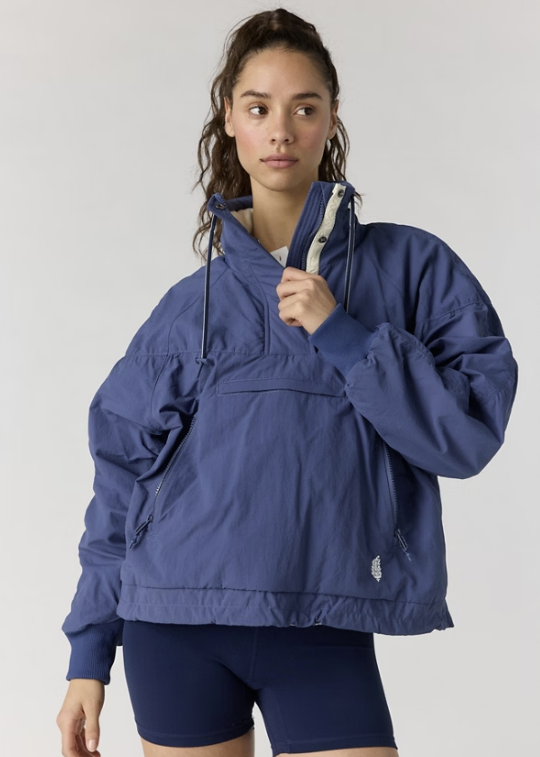 Woman wearing navy pullover jacket with navy bike shorts on plain background