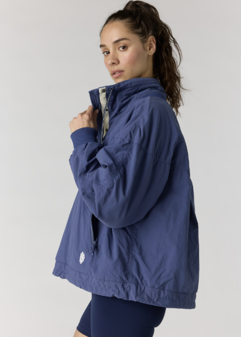Woman wearing navy pullover jacket with navy bike shorts on plain background