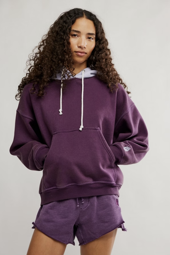 Person wearing a purple hoodie and shorts set on a plain background