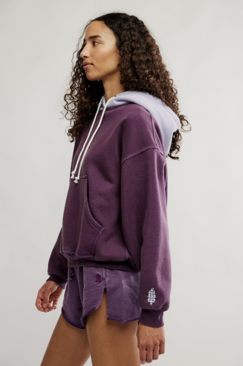 Person wearing a purple hoodie and shorts set on a plain background