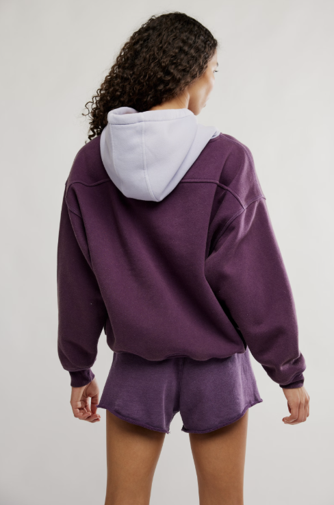 Person wearing a purple hoodie and shorts set on a plain background
