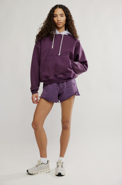 Person wearing a purple hoodie and shorts set on a white background