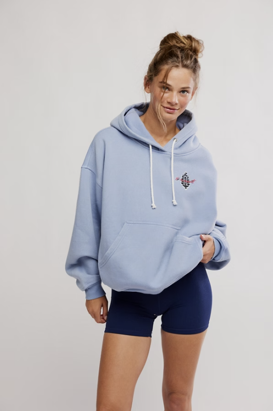 Woman wearing light blue sweatshirt with logo and bike shorts on white background