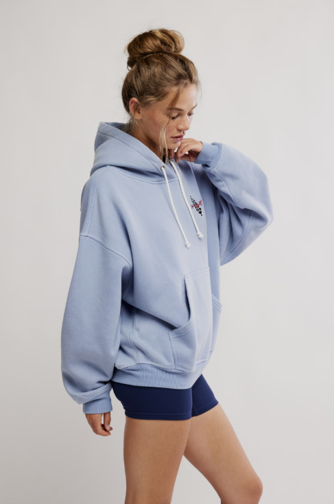 Person wearing a light blue hoodie and dark shorts on a plain background