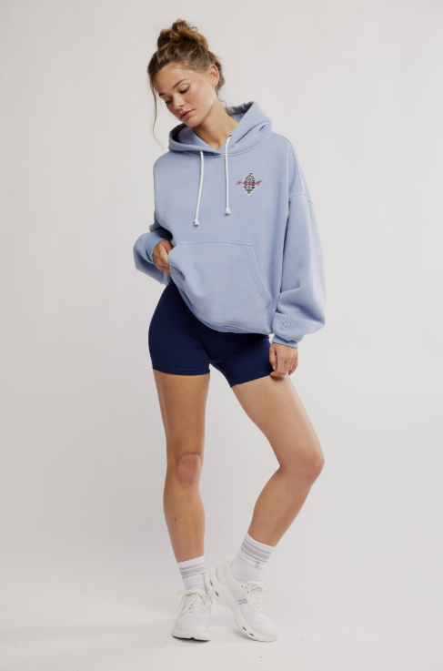 Woman wearing a light blue hoodie with a logo on a white background