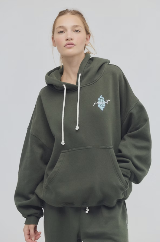 Person wearing a green hoodie with a logo on a plain background