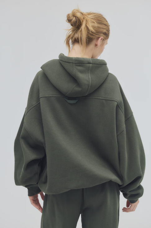 Person wearing a green hoodie and pants on a plain background