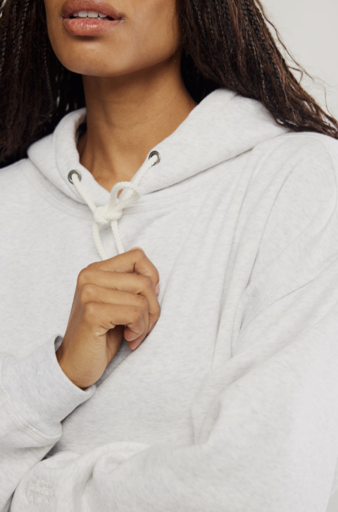 Close up of woman wearing light grey sweatshirt on white background