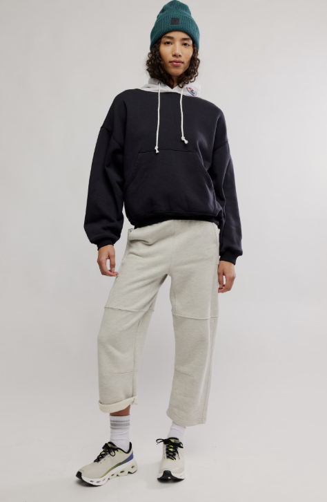 Person wearing a black hoodie, beige pants, and a green beanie on a white background