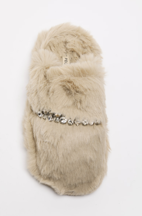 A single fluffy faux-fur slipper in a light beige or cream tone, decorated with a horizontal row of clear rhinestone embellishments across the center, shown against a plain white background.