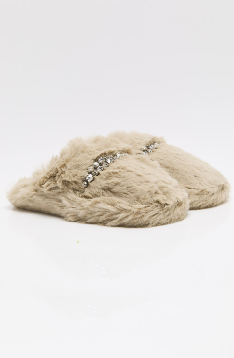 A pair of beige faux fur slippers with a decorative silver rhinestone embellishment across the top, set against a plain white background.