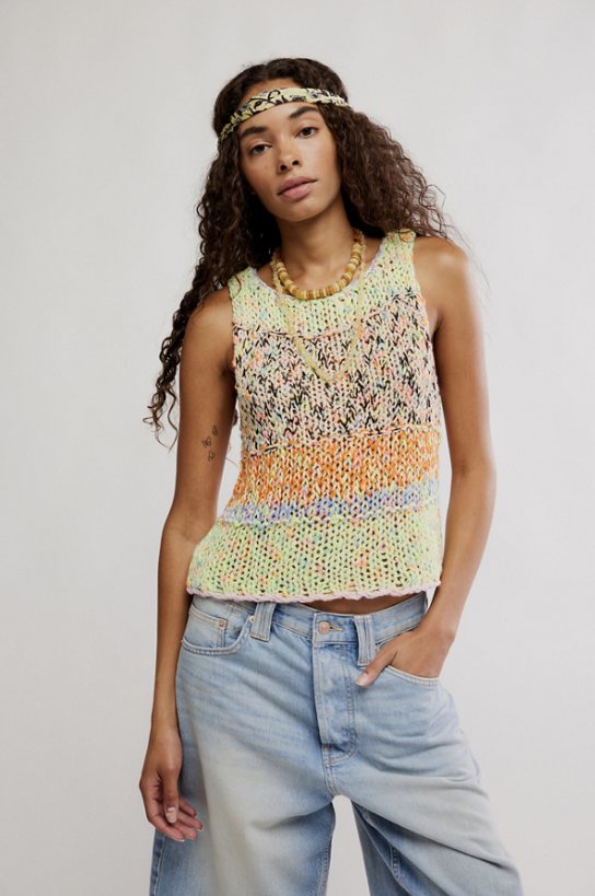 Woman wearing a colorful sleeveless top and light blue jeans against a plain background