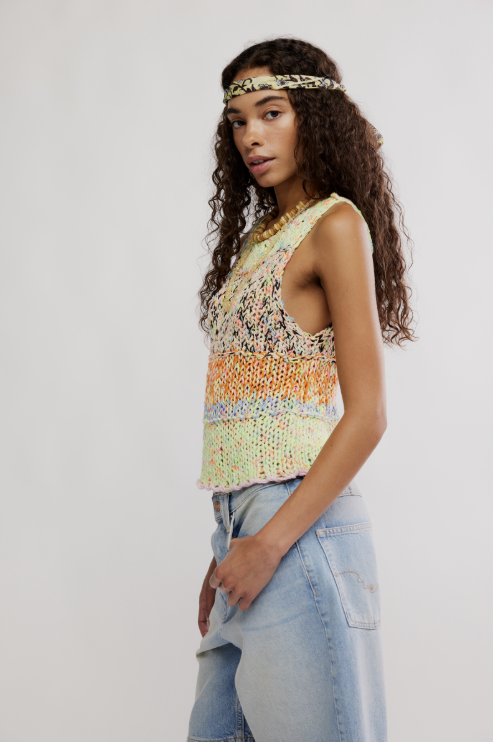 Woman wearing a colorful sleeveless top and light blue jeans on a white background