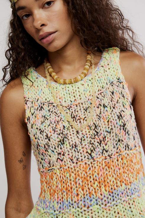 Woman wearing a colorful crochet tank top with a neutral background