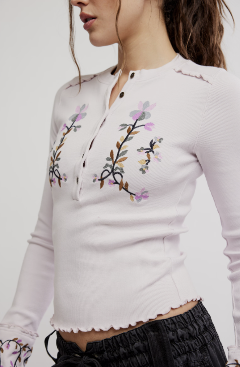 White long-sleeve top with floral embroidery on a plain background