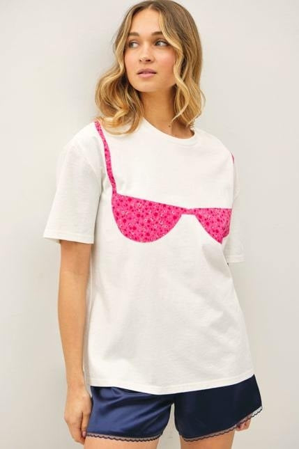Woman wearing white tee with pink floral bikini print on plain background