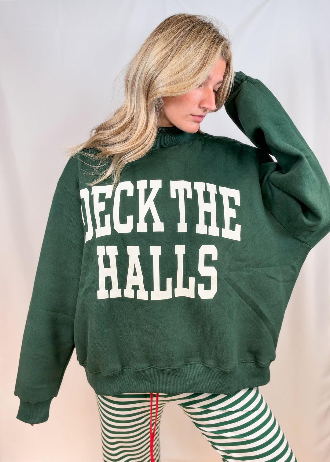 Woman wearing green mock neck sweatshirt with &