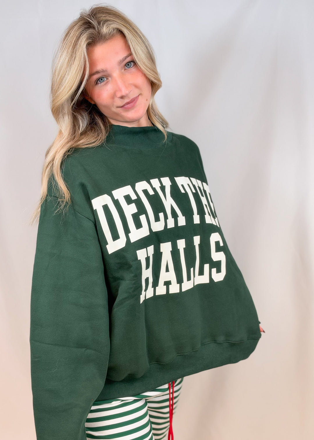 Woman wearing green mock neck sweatshirt with &
