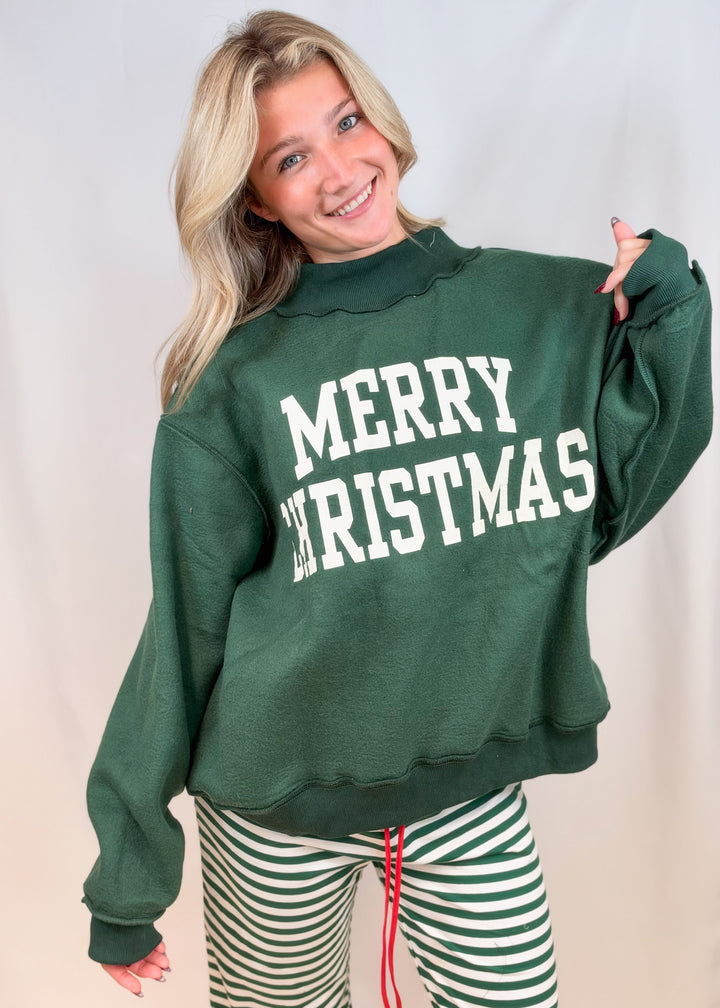 Woman wearing green mock neck sweatshirt with &