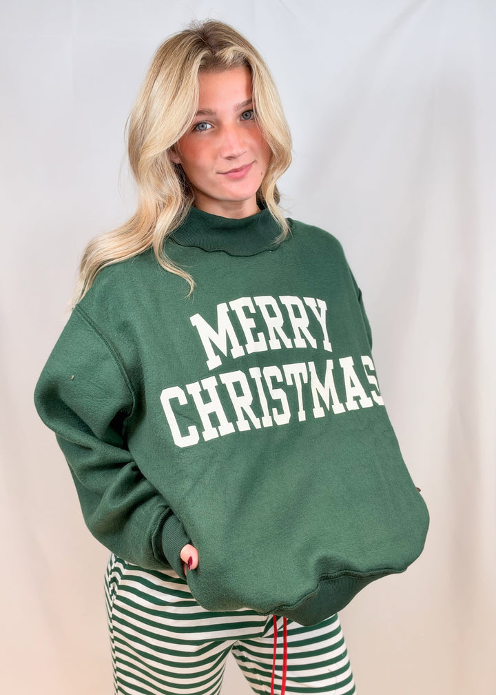 Woman wearing green mock neck sweatshirt with &