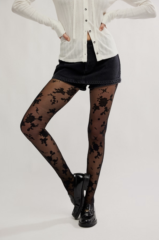 Woman wearing flocked floral tights in black and black shorts on white background