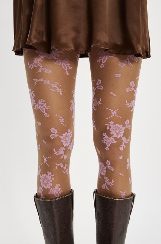 Woman wearing pink flocked floral tights and brown skirt on white background