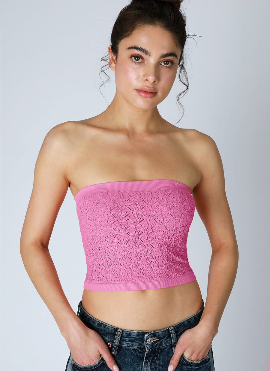 Woman wearing a pink tube top against a plain background