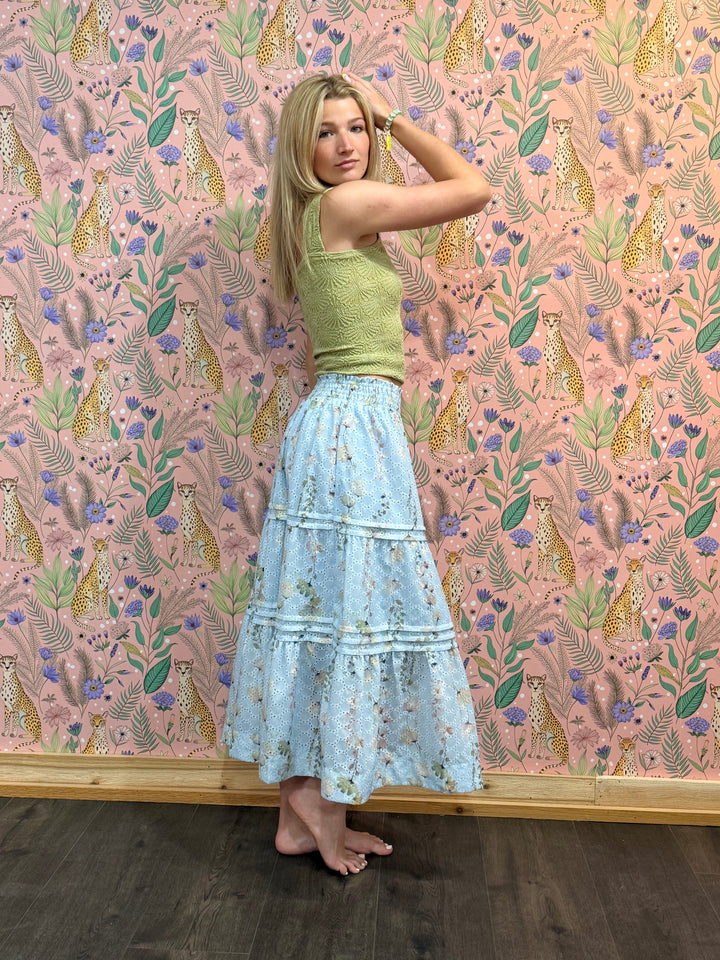 Woman posing in front of a wall with a colorful animal and floral pattern.