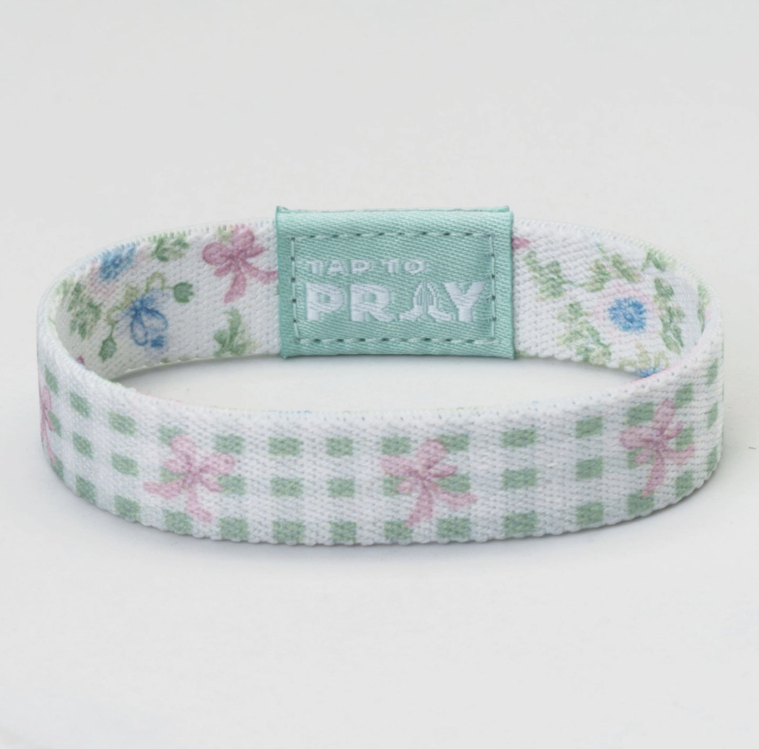 Bracelet with floral pattern and 'Tap to Pray' tag on a white background