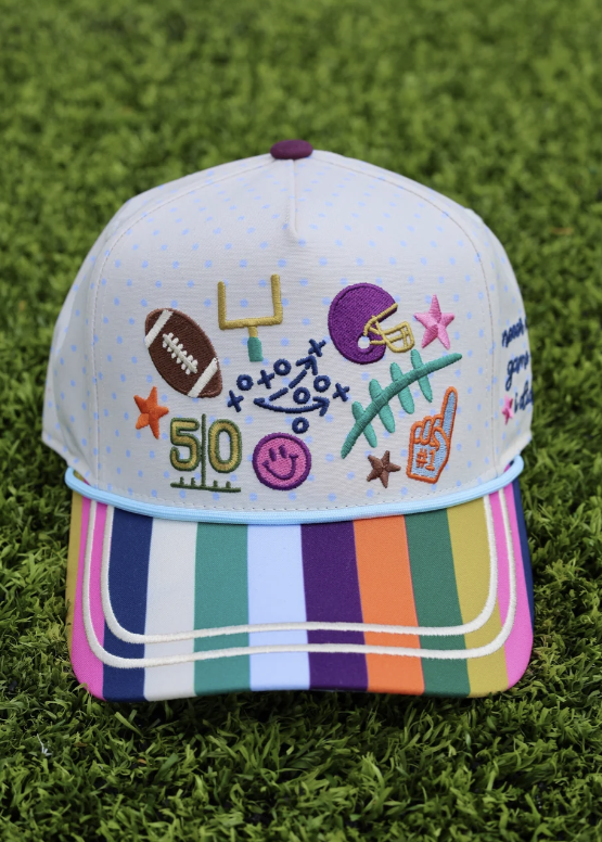 Trucker hat with football doodles embroidered with a striped bill on grass