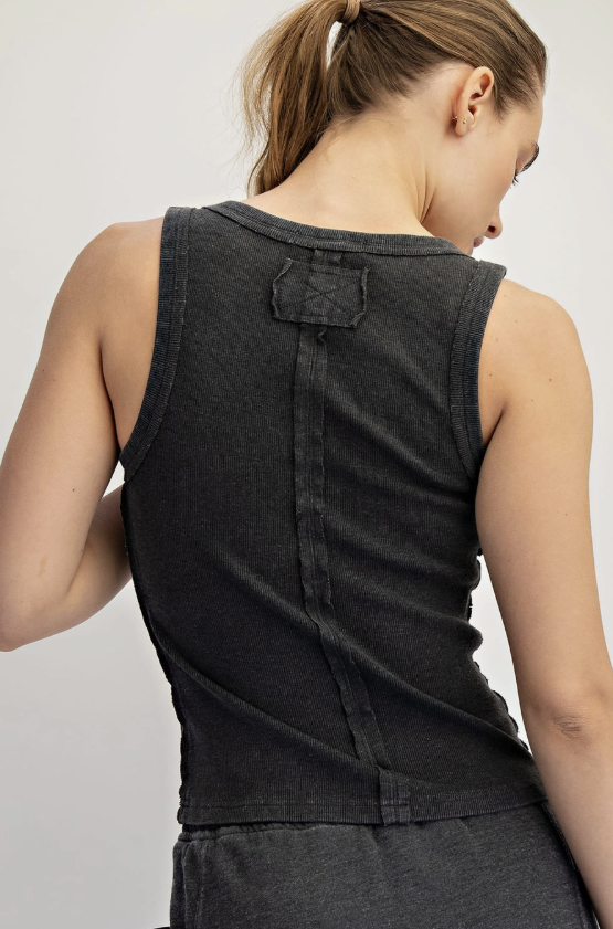 Person wearing a black sleeveless top on a plain background