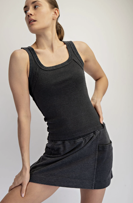 Woman wearing a black tank top and skirt on a plain background