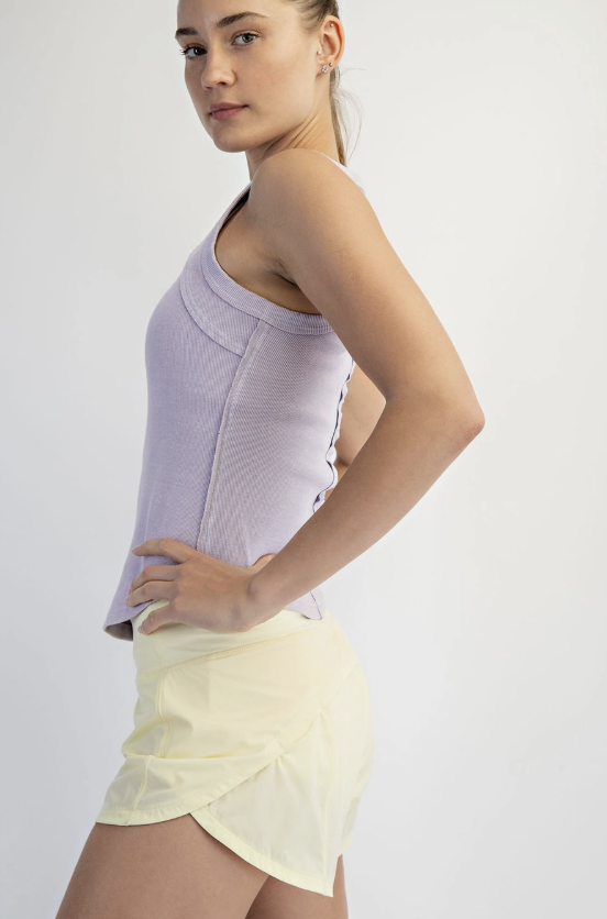 Woman wearing a light purple top and yellow skirt on a white background