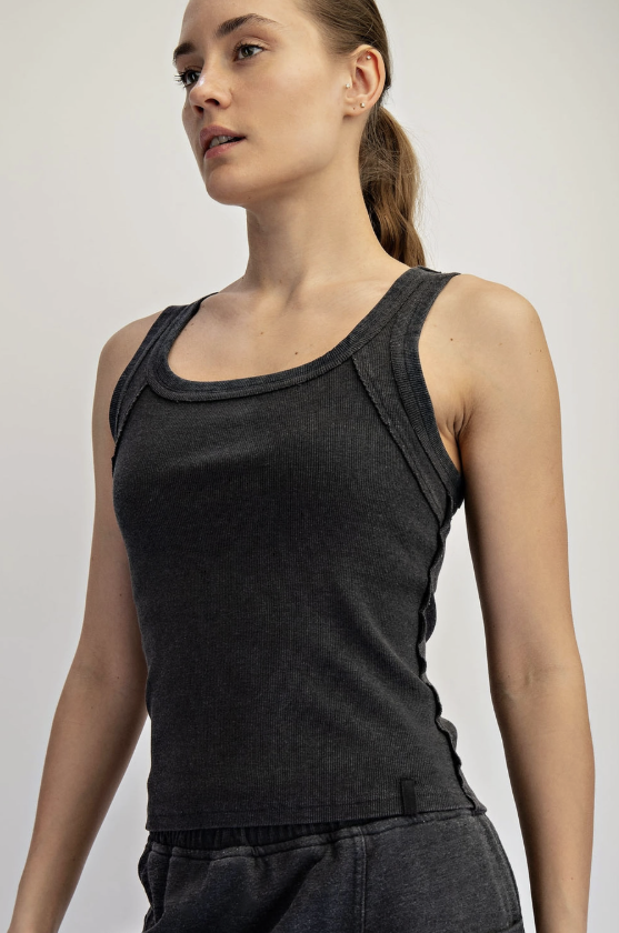 Woman wearing a black tank top against a plain background