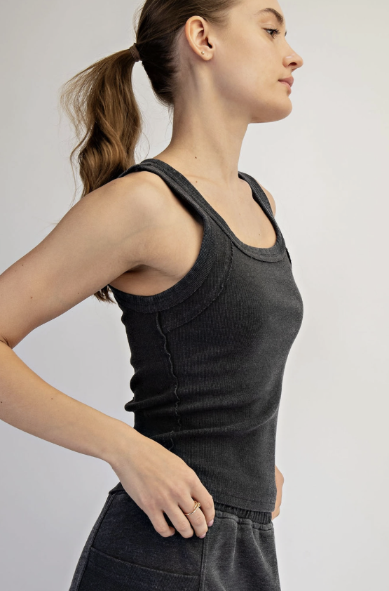 Woman wearing a black tank top against a plain background
