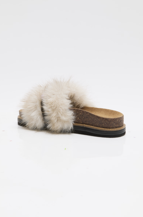 A single slide sandal with a fluffy cream fur strap, a brown textured footbed, and a black sole, shown from a side profile on a white background.