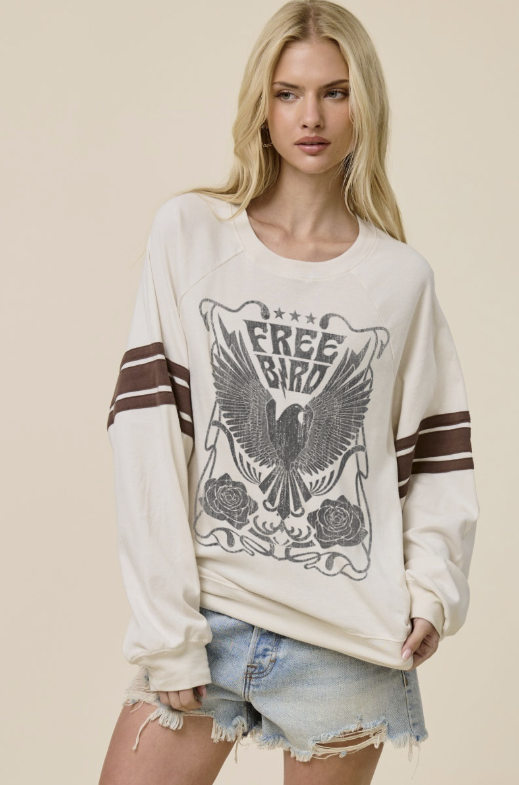 A blonde model wearing a cream-colored crewneck sweatshirt with a distressed graphic of an eagle and the words &