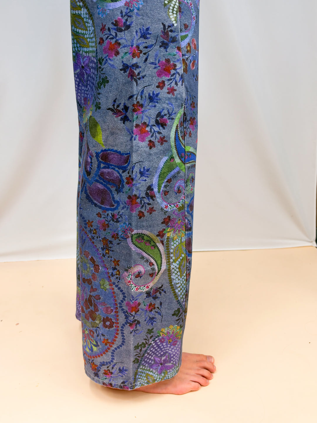 Close up of blue paisley jeans on plain background