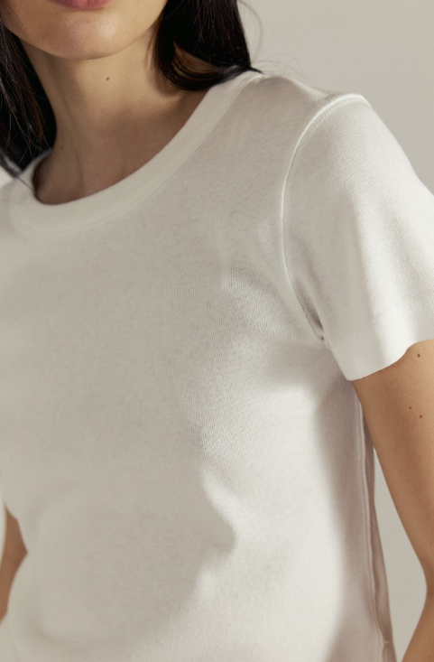 Close-up of a person wearing a plain white t-shirt against a neutral background