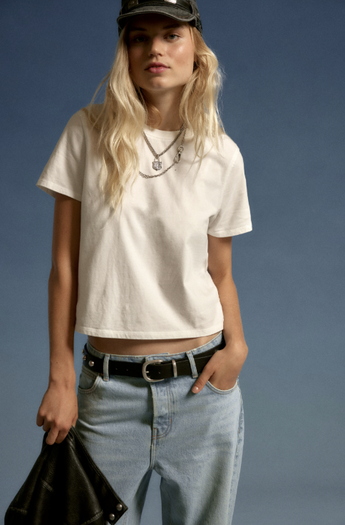 Person wearing a white t-shirt and light blue jeans against a blue background