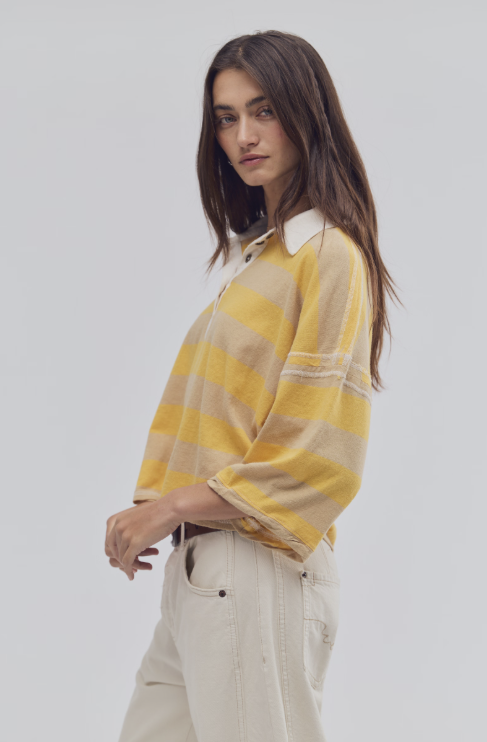 Woman wearing a yellow and white striped shirt against a plain background