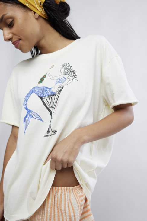 Woman wearing a white t-shirt with a mermaid design on a plain background